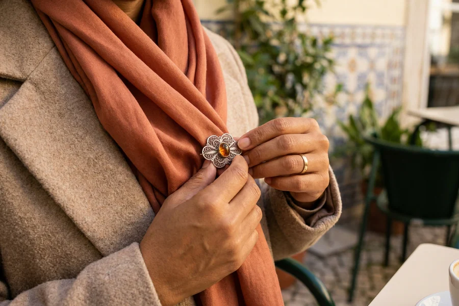 Mãos a colocar um broche sobre duas camadas de lenço